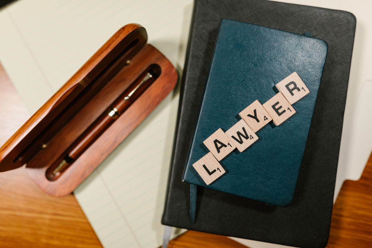 Crafting Captivating Headlines: Your awesome post title goes here Scrabble tiles spelling 'LAWYER' on a blue notebook with a wooden pen case, overhead view.